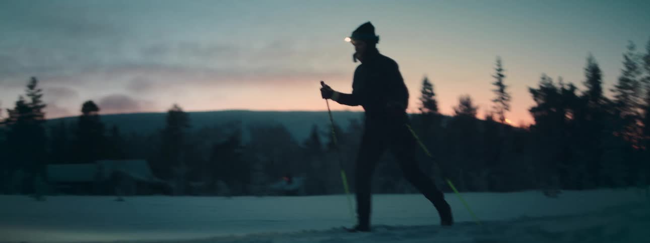 A woman skiing in the snow during dawn