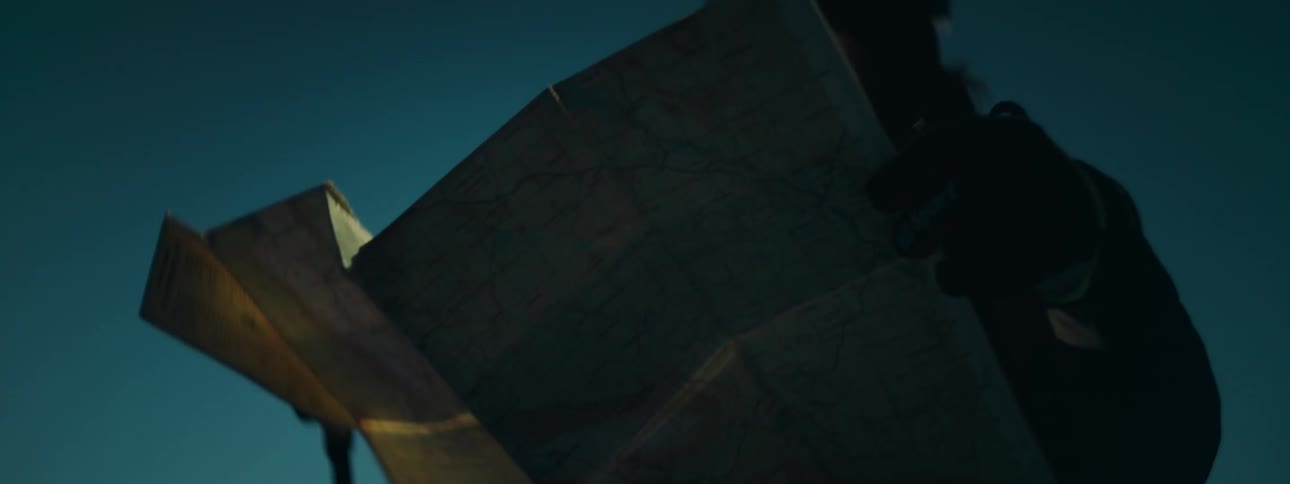 Woman wearing a headlamp looks at a paper map at night