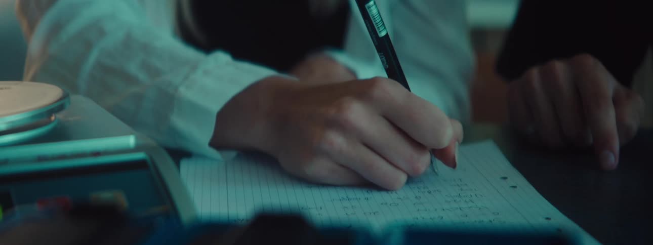 A person writing calculations on a sheet