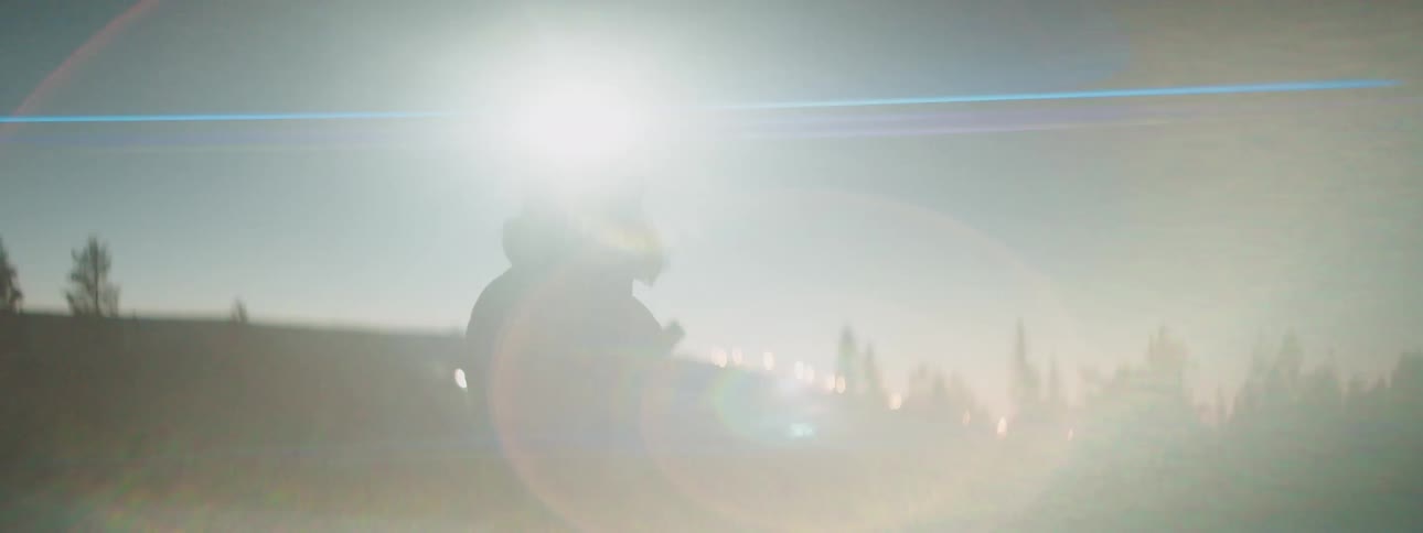 Woman wearing a headlamp skiing in a snow field at nightfall