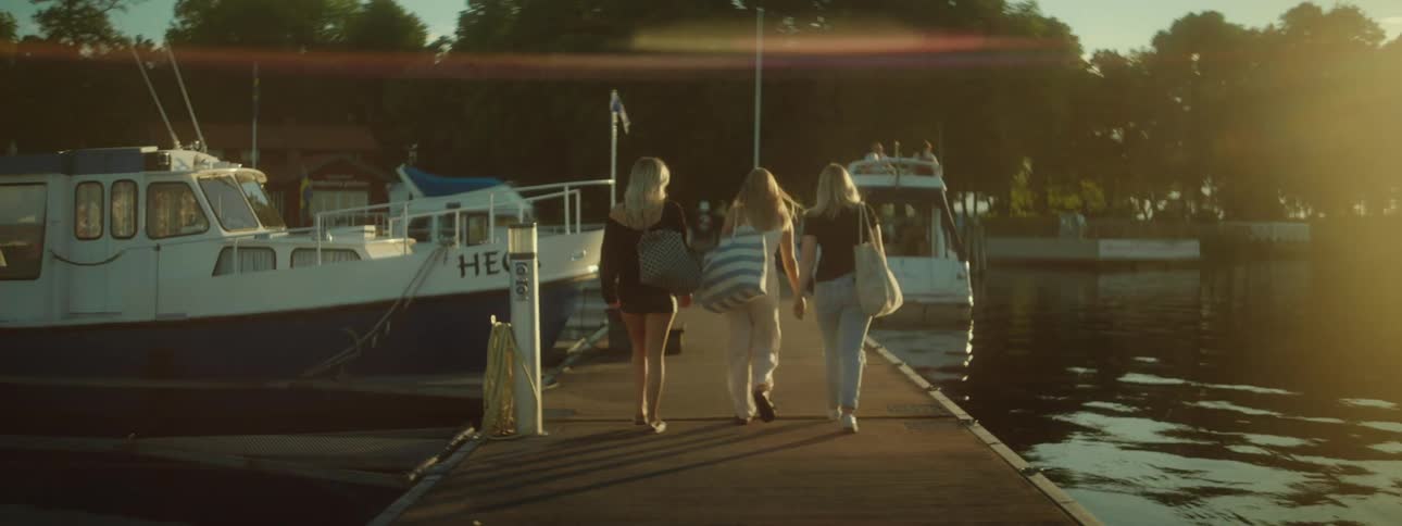 Back view of three girls walking on a dock in a late afternoon
