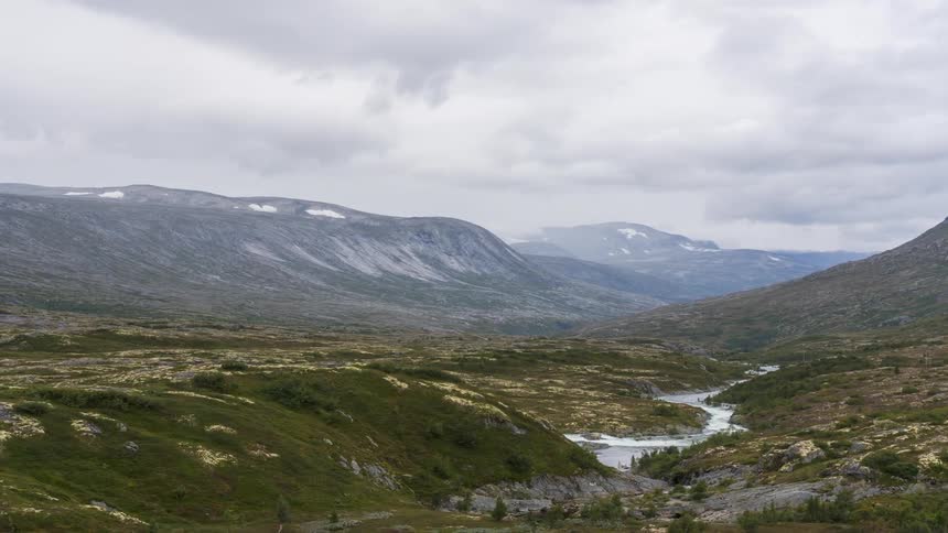 A river curves through a rocky landscape in the mountains on a cloudy day
