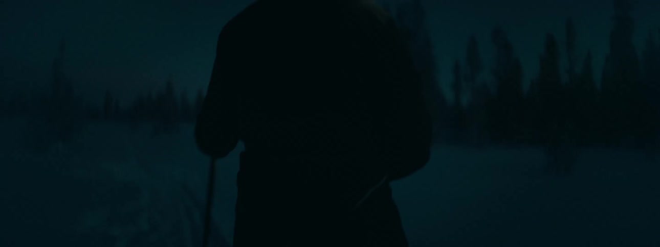 A woman with a flashlight on her head looks around outdoors