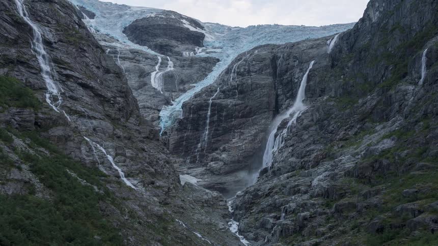 A waterfall from a glacier falls down a mountainside