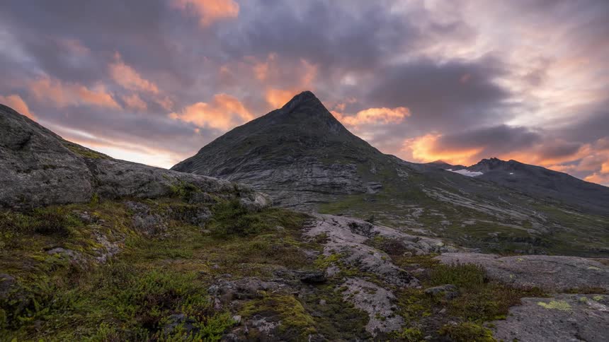 A sunset view of a mountain landscape with a prominent peak
