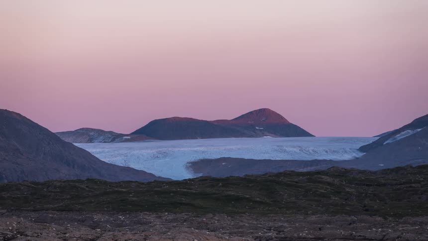 A large glacier sits in a mountain valley