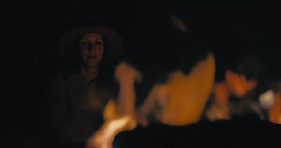 A woman at night in front of a campfire