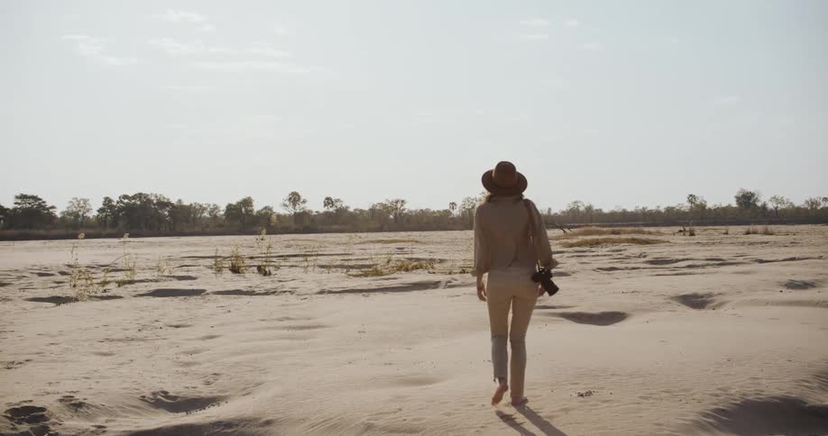 A woman walking barefoot in the desert on a sunny day