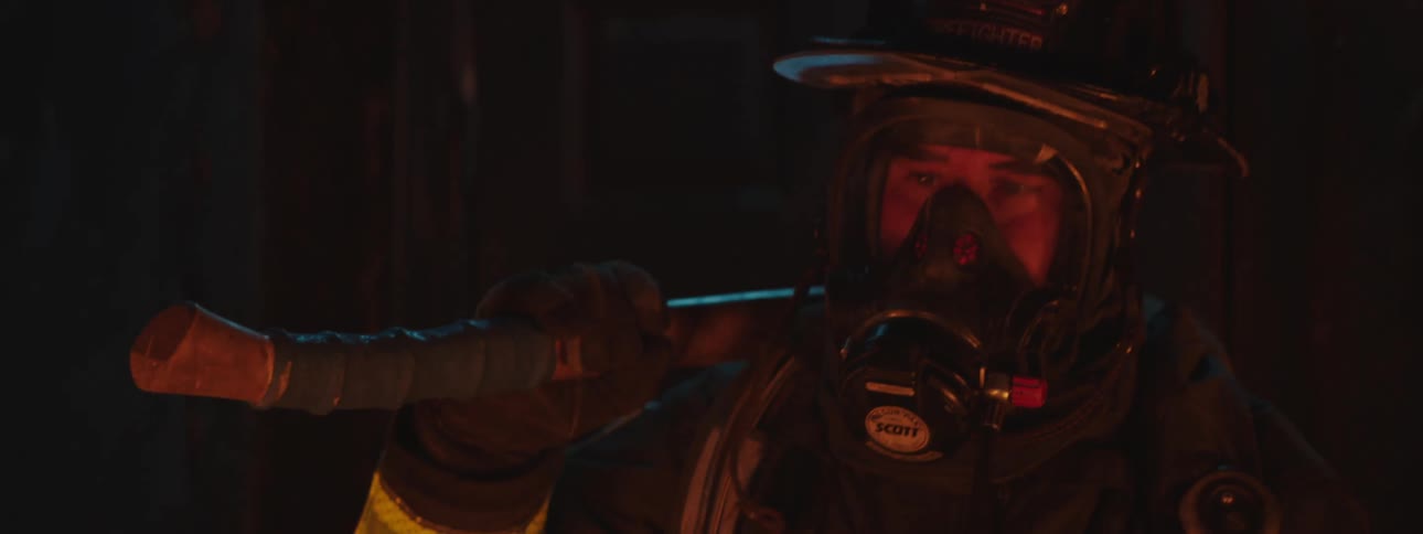 A fire fighter in full protection gear puts an ax to his shoulder