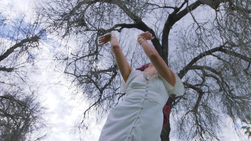 A teenage girl moves her body in a forest