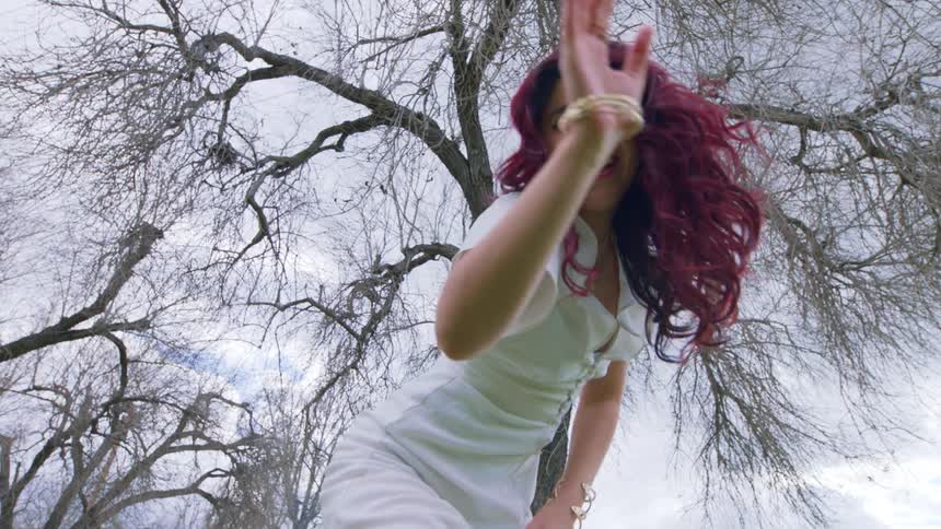 A woman is dancing under the tree