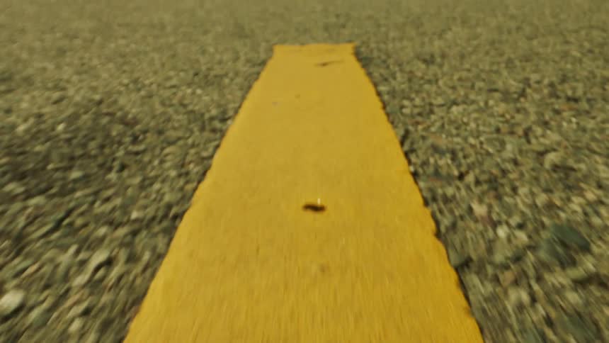 A closeup view of a yellow road marking on an asphalt surface