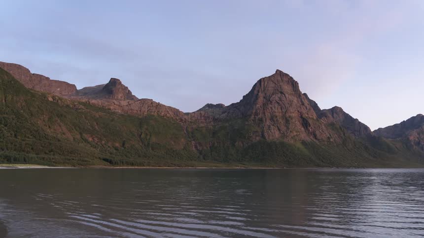 A time lapse of a mountainlined shoreline shows numerous waves coming ashore