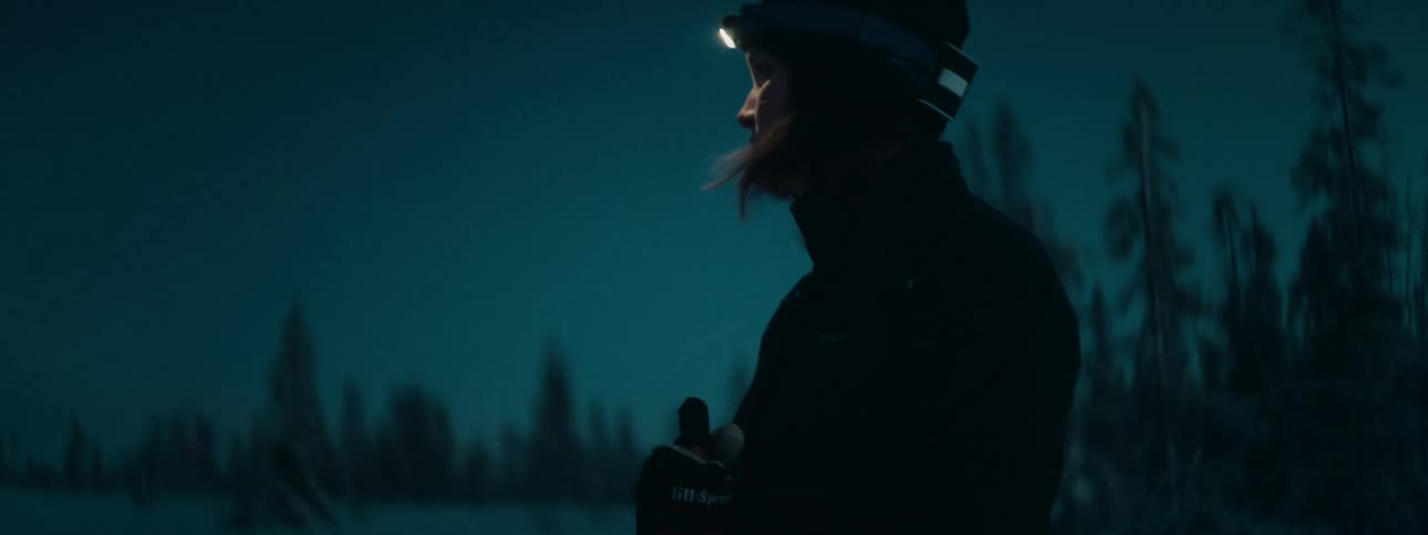 A woman searches around with a headlight at night