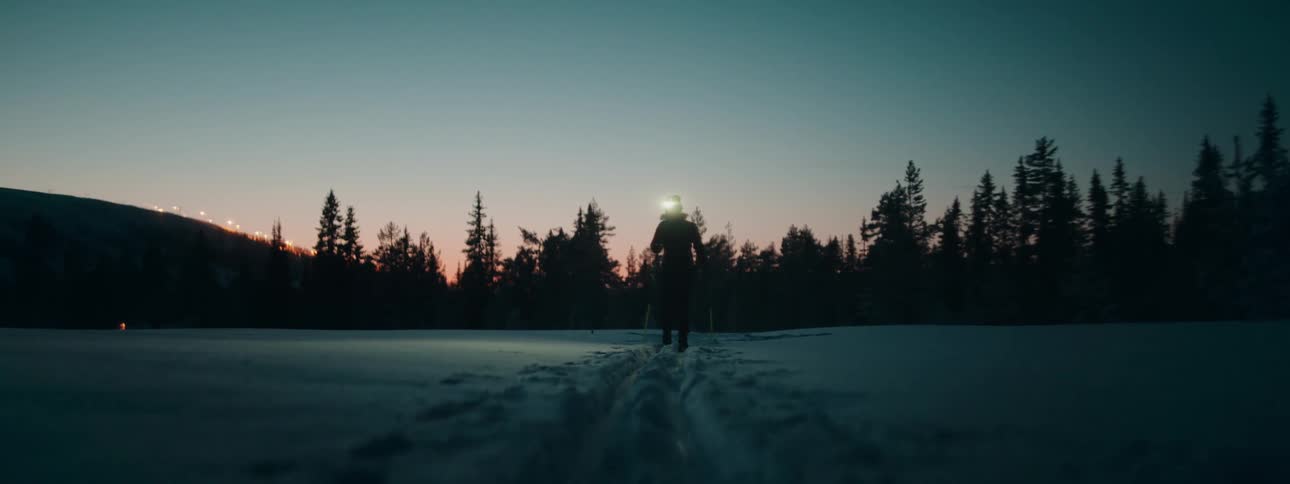 A woman cross country skis across a snow covered field
