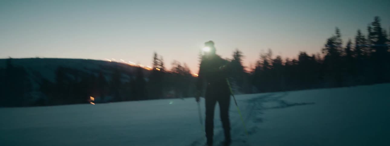 A person skiing in the snow with a headlamp
