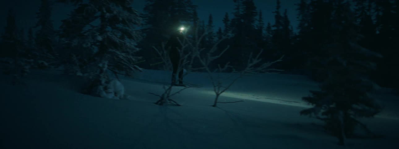 Skier with head lamp illuminates the snowy slope at night