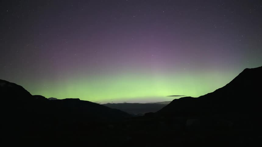 An aurora shines near mountains