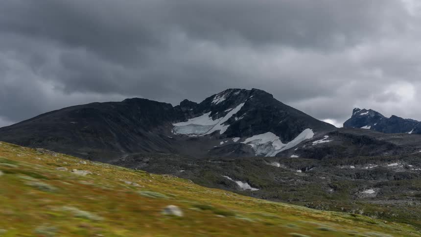 A grassy hill in front of a large mountain