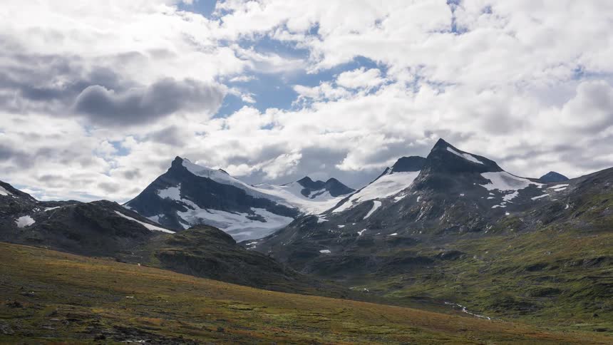 Landscape with mountain ranges with snow and clouds passing by in time lapse