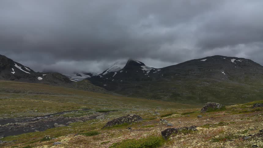 Landscape of mountains with snow and clouds passing by in timelapse