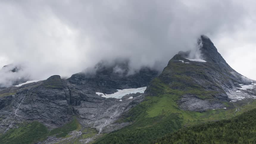 Clouds swirl around a mountain peak