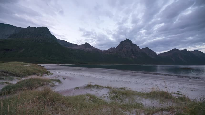 Time lapse of a day in the lake surrounded by a mountain range under clouds