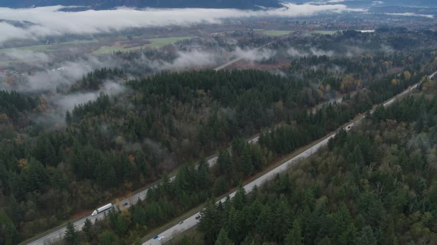 Pullback reveal of an interstate highway surrounded by mist shrouded forest and mountains