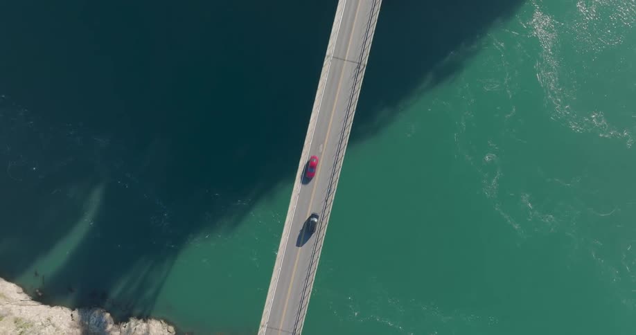 Birds eye view of cars on a high two lane suspension bridge over aquamarine water