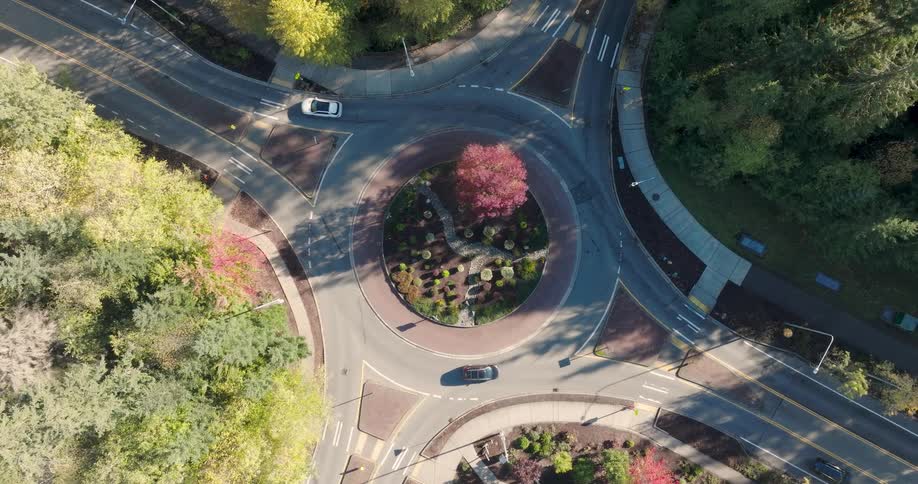 Cars smoothly circle a roundabout in a suburban neighborhood