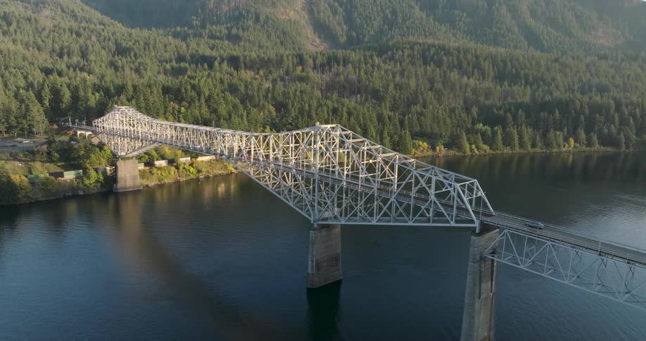 Slow approach over the trees towards a large bridge crossing over a wide river