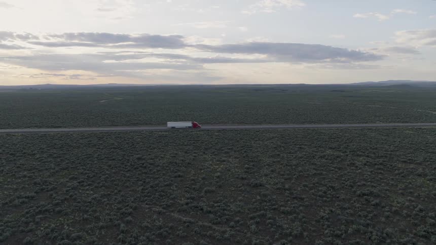 Wide approach towards an eighteen wheeler truck driving on open road through the American west