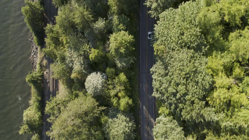 Top down view of a white sports car traveling on a cliffside road