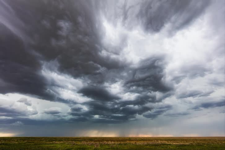 A tornado with lightning lighting up the meadow during a thunderstorm