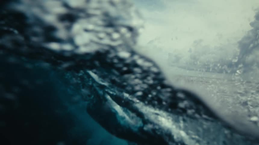 A man making video of the water waves while standing inside the sea at daytime