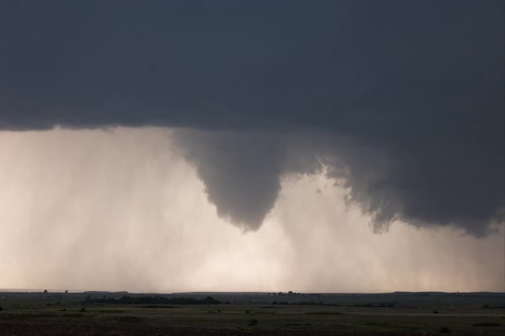 Storm clouds move across the sky as a funnel cloud moves over the ground