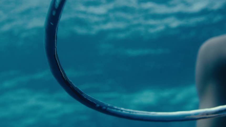 Underwater footage of a person and a ringed air bubble rising to the surface