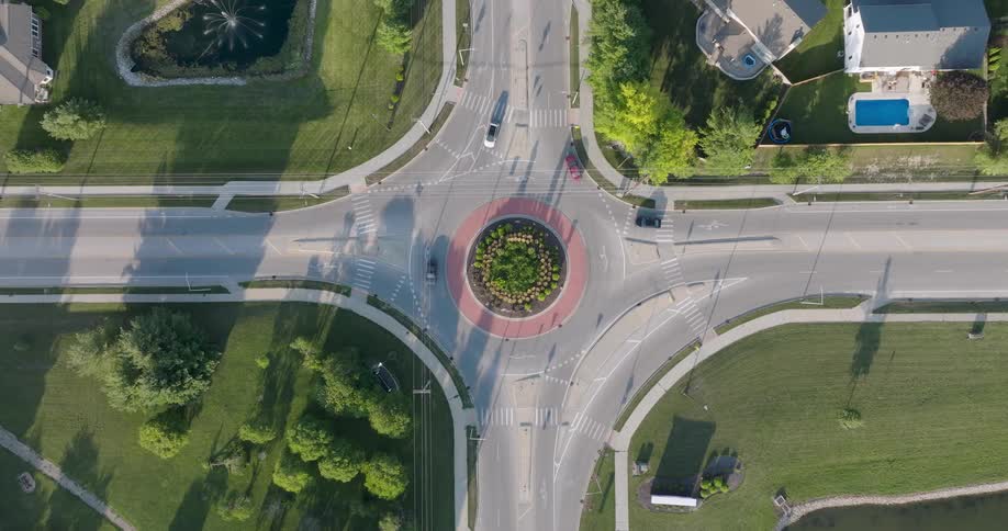 Top down view of a roundabout intersection in a peaceful suburban neighborhood