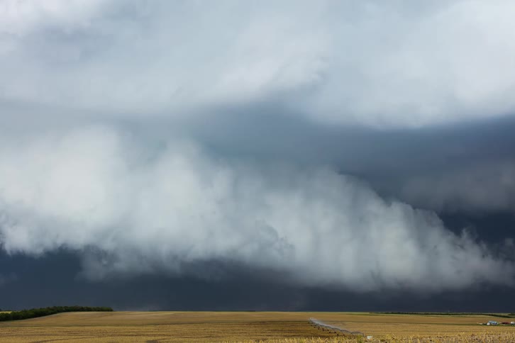 Clouds move over a dark stormy sky as rain pours on the ground