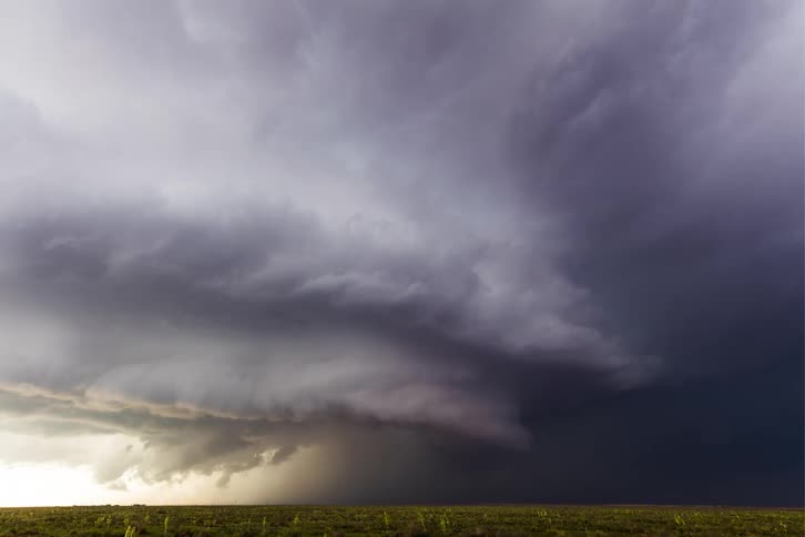 Dark storm clouds move across the land pouring rain as lightning flashes