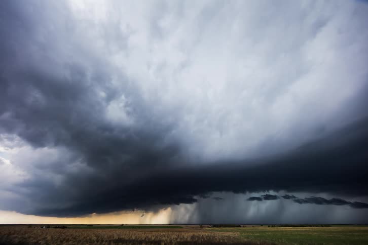 Storm clouds spiraling over flat rural farmland