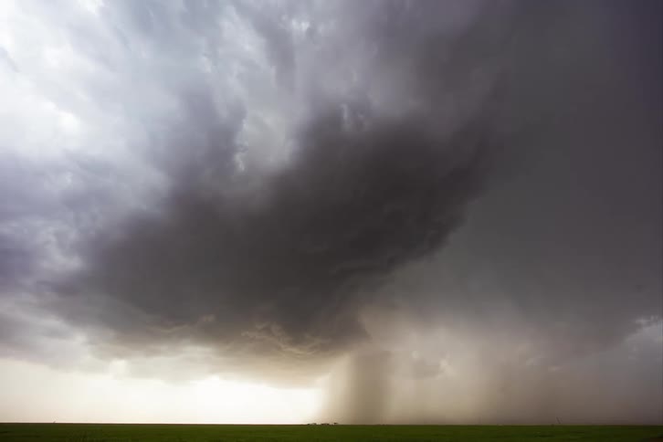 Storm clouds move across the sky as rain pours onto the ground