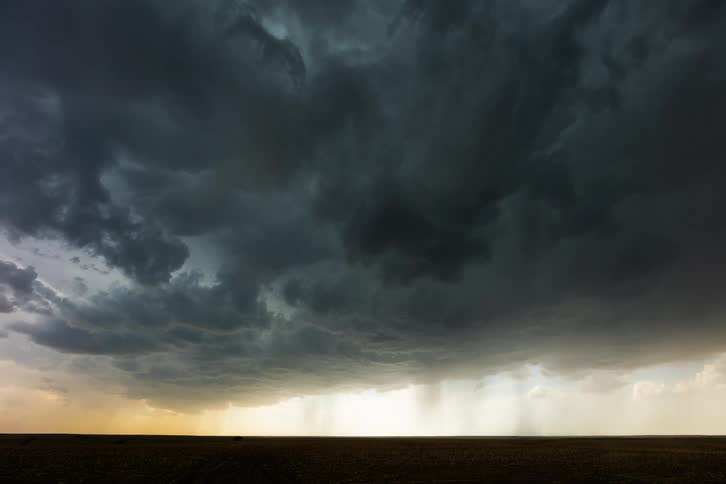 Dark storm clouds move across the sky as rain falls and lightning flashes