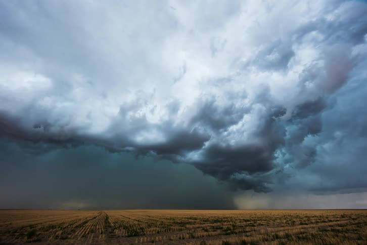 Dark storm clouds pour rain on rural farmland as lightning flashes