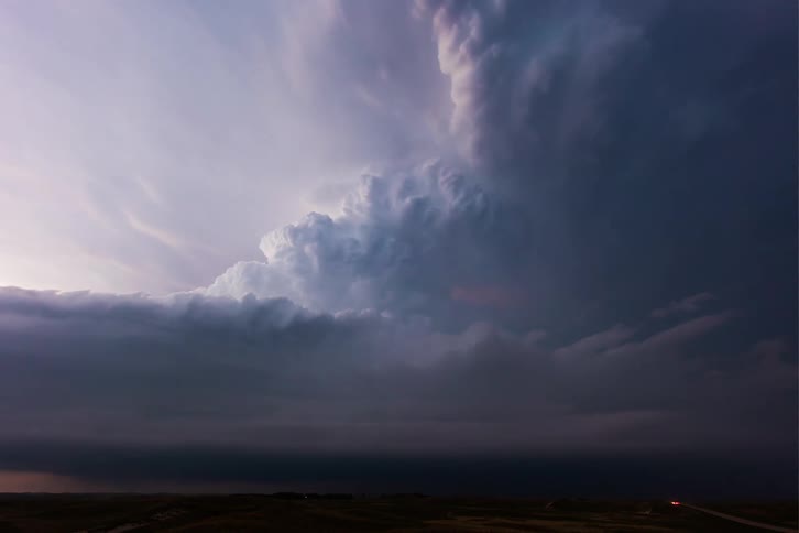 Clouds gather ominously heralding an approaching storm with flashes of lightning illuminating the darkening sky