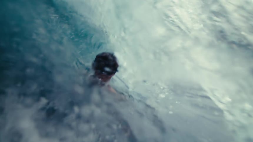 A person swimming in the ocean submerges under a wave