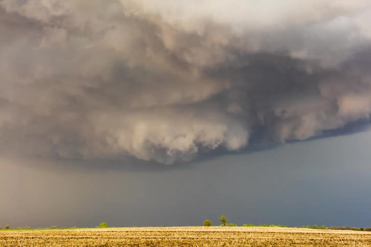 Storm clouds move over farm land as lightning flashes and strikes the ground