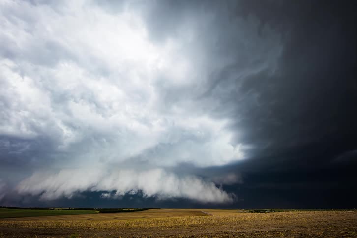 Dark storm clouds flow and rotate over plains during the day