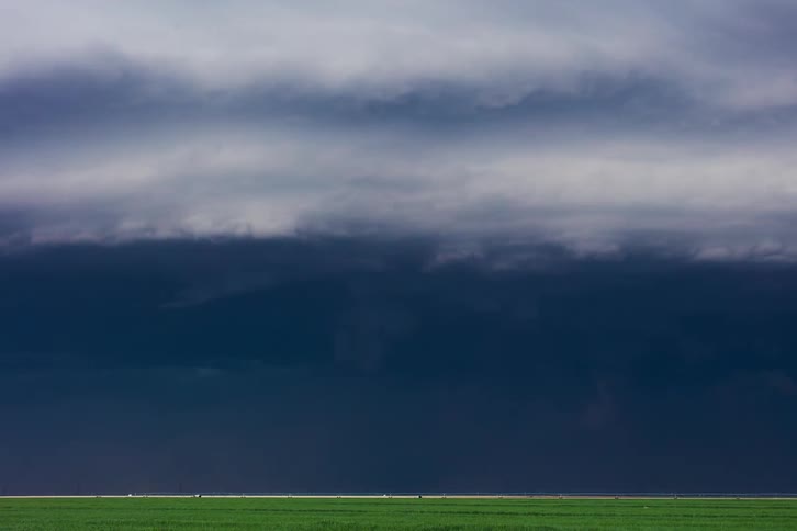 Ominous dark clouds move over a rural area and pour down rain as lightning flashes