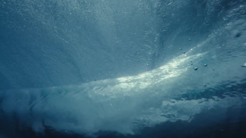 Inside the sea a wave forming and breaking with solar reflection